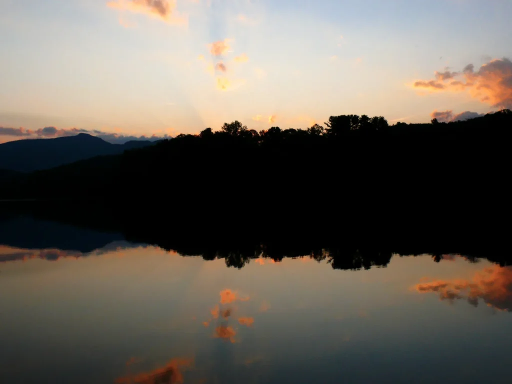 Orange sunset clouds reflected in still water at Price Lake beneath dark mountain silhouettes